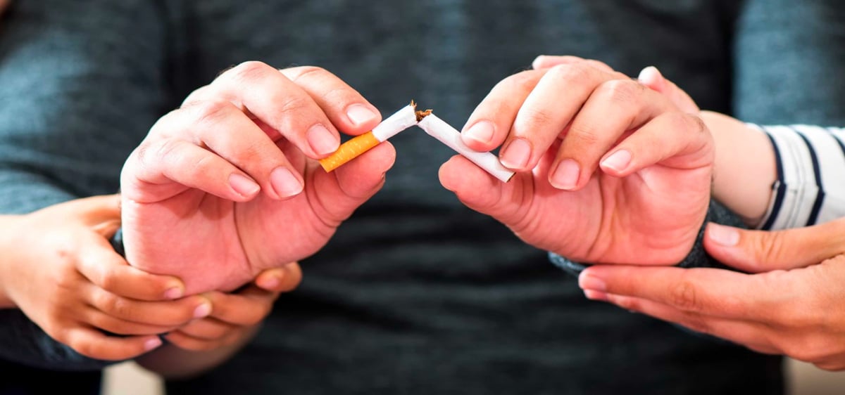 A close up image of hands breaking a cigarette in half.