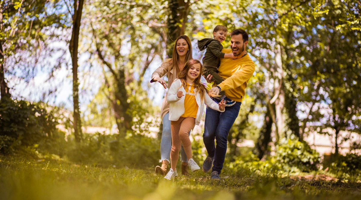 A family running through the woods on a sunny day.