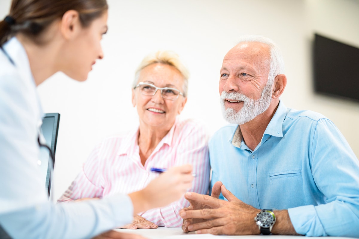 A female physician explaining treatment to a senior couple.