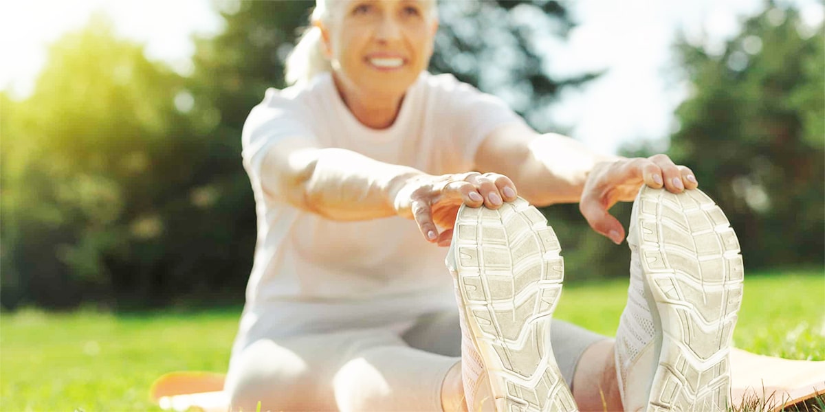 A senior woman stretching outdoors.