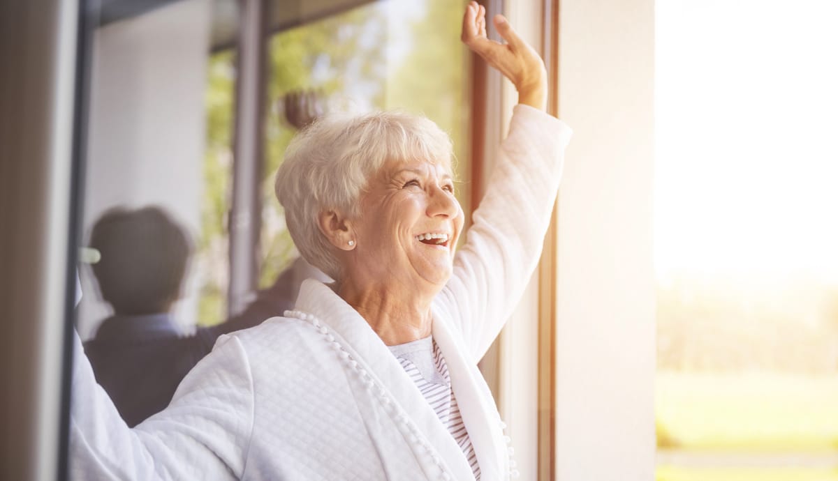 A senior woman stretching at the window in the morning.