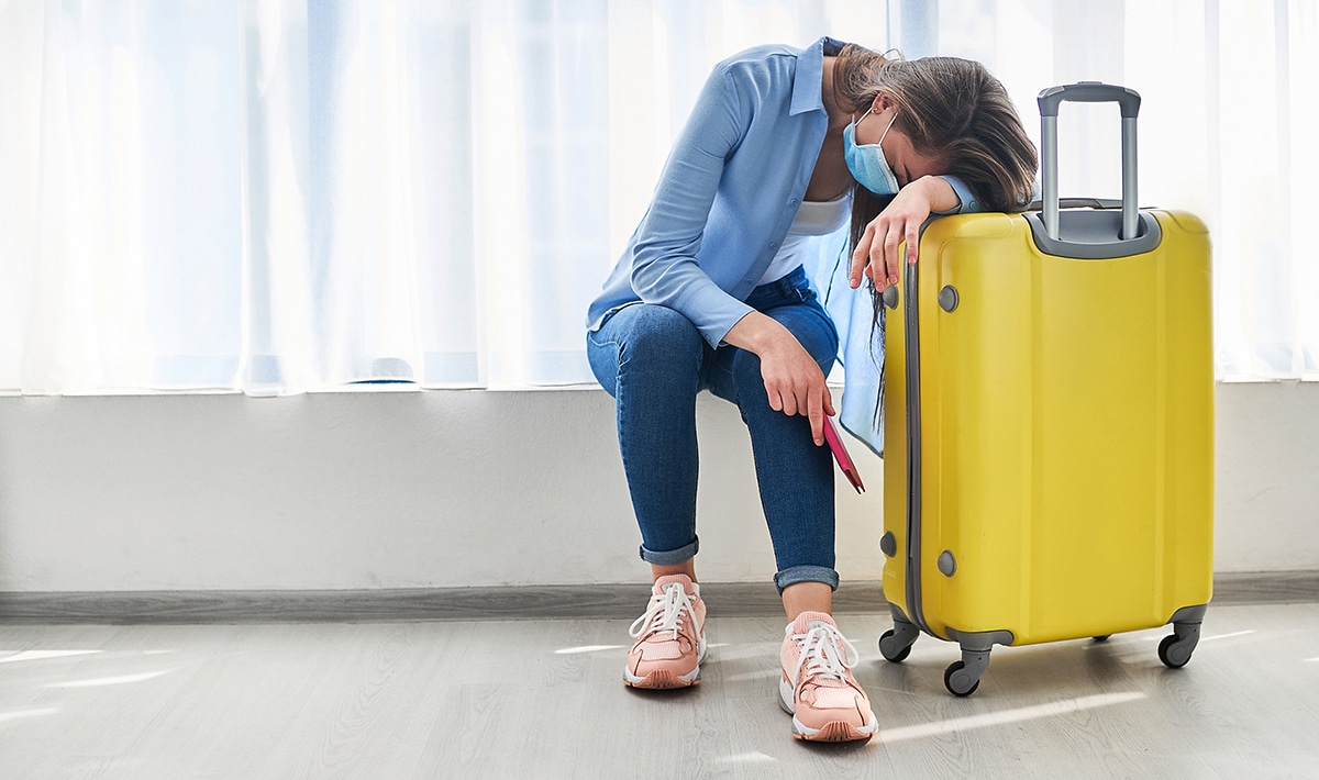 Woman traveler in face protective mask affected by flight delay and cancelled travel and vacation. Travel ban due to coronavirus outbreak and covid-19 ncov virus epidemic